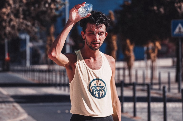 Tired sportsman pouring water on head after running training